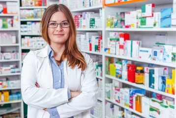 Poster de jardin Pharmacie Cheerful pharmacien chimiste woman standing in pharmacie drugstore