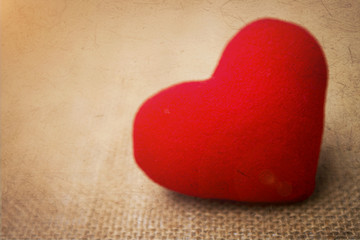 Fototapeta premium Vintage Valentine background, red heart on hessian texture with vintage filter