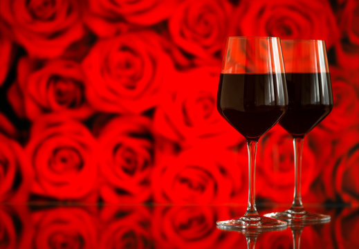 Two glasses of red wine against bokeh background with sparkles and roses. Very shallow depth of field. Selective focus, copy space