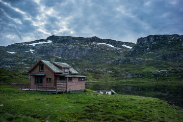 Fototapeta na wymiar Old house in Norwegian lake and dramatic sky