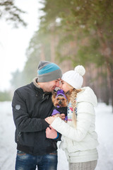 A couple with a small dog on a walk in the winter woods