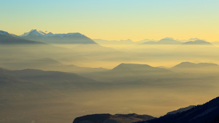 Colorful dusk in the French mountains, with the valley filled with fog.