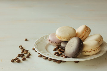 Different macarons on white dish and coffee beans