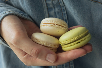 Hand holding cream and green macarons