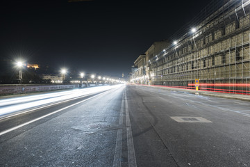 Strada su lungarno fiorentino di notte con luci artificiali e strisce di luce delle macchine