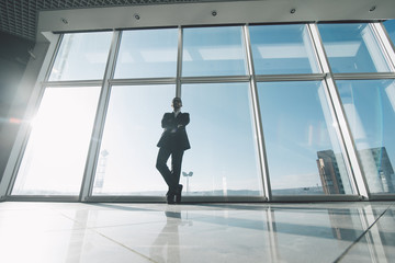 King of market. Young success business man standing satisfy against panoramic windows