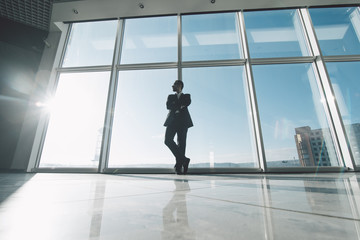 Fototapeta premium King of market. Young success business man standing satisfy against panoramic windows