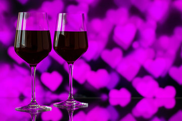 Two glasses of red wine against bokeh background with sparkles a