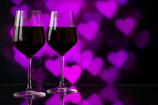 Two glasses of red wine against bokeh background with sparkles a
