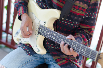 .Young Living and practicing electric guitar happily at home. © Tongra