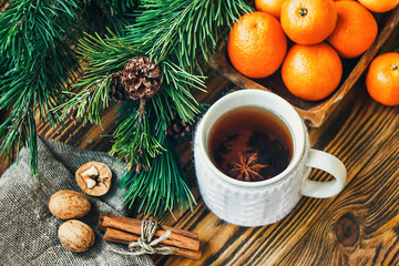Obraz na płótnie Canvas Christmas New Year composition winter holiday celebration concept symbol tangerines clementine nuts pine cones fir branches cup tea rustic style old wooden board selective focus festive greeting card