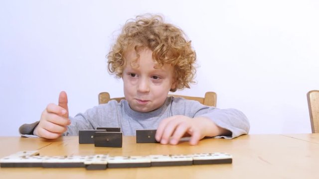 little blond boy playing with dominoes