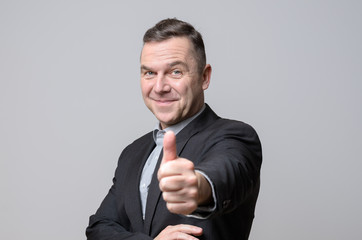 Grinning man in suit with thumb up