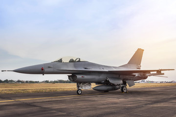 f16 falcon fighter jet military aircraft parked in the runway on sunset  