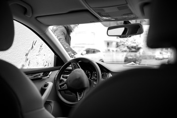 Businesswoman cleaning the car windshield from snow after a snow storm - view from inside the car
