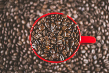 Coffee beans in red cup, mug macro close up detailed well roasted in vivid colors overhead shot. Concept for freshness, morning, cozy lifestyle.