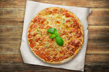 Pizza quattro fromaggi with basil on wooden planks