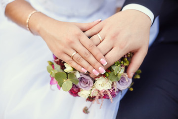 Obraz na płótnie Canvas Hands of bride and groom on wedding bouquet. Marriage concept
