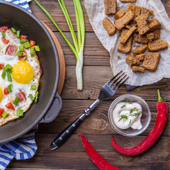 Fred eggs in pan with tomatoes and green fresh onion.