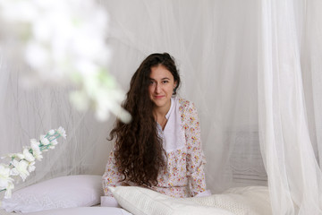 young girl sitting on a white bed in dress © veksler
