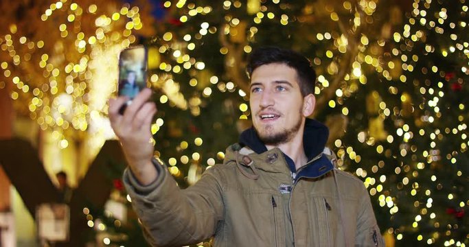 a boy with blue eyes at Christmas take a picture in front of the Christmas tree in a shopping center. concept of celebration, happiness and user friendly technology. live streaming tecnology.
