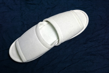White cloth slippers on blue background in spa service.