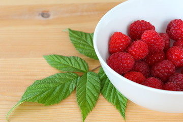 red raspberry fruits in a small white bowl