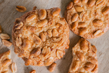Salted crunchy peanut cookies freshly baked with crumbs and pieces on a wooden plate top down view