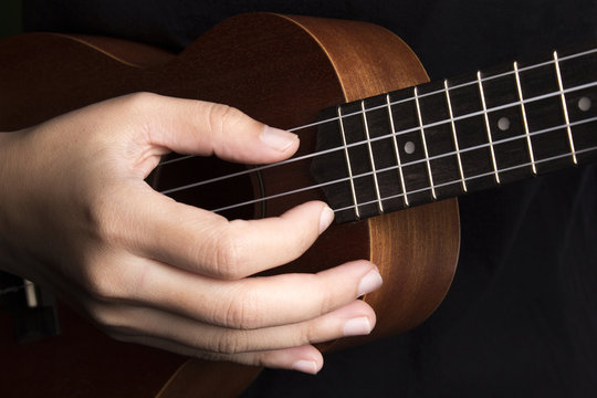 Somebody playing ukulele in close up view.