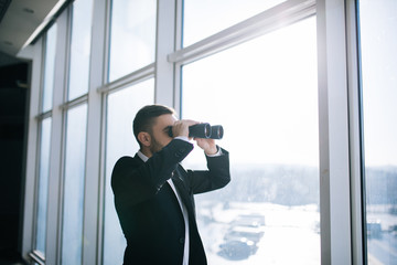 Businessman with binoculars spying on competitors.