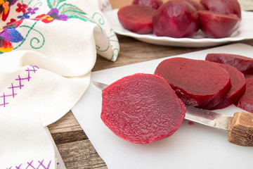 Cutting beetroot on white chopping board over on old wooden tabl