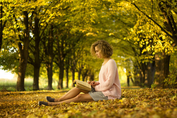 woman is reading book in the autumn park