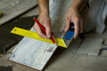 Fototapeta na wymiar Worker installing Tiles on the Floor. Measurement of ceramic tile.
