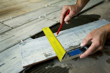 Worker installing Tiles on the Floor. Measurement of ceramic tile.