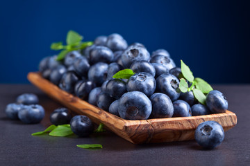 blueberries with green leaves in wooden dish