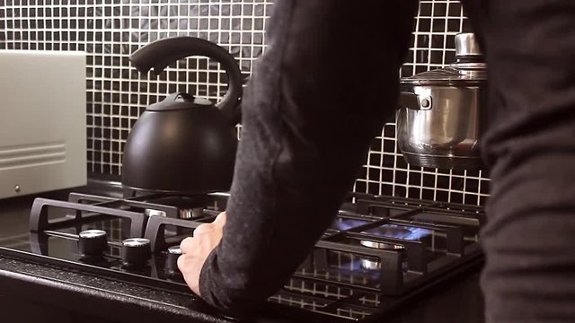 Man In The Kitchen To Put The Kettle On A Gas Stove.