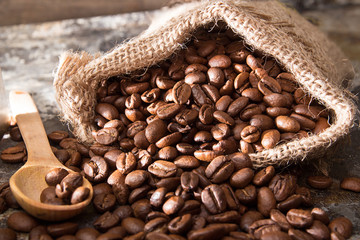 Roasted coffee beans in small sack on metal surface