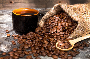 Roasted coffee beans in small sack and cup of coffee