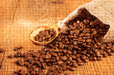 Roasted coffee beans in small sack on wooden table