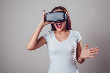 Attractive and happy woman using virtual reality goggles on grey background. VR headset.