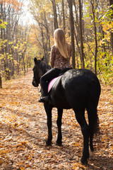girl walking in the autumn forest on horseback
