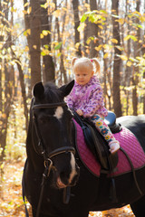Obraz na płótnie Canvas little girl walks in autumn forest with a horse