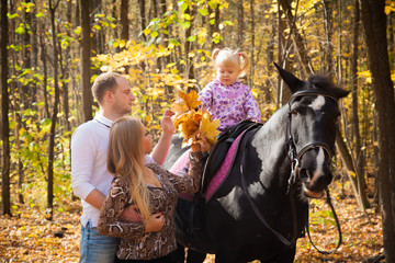 Fototapeta premium young family walking in the autumn forest with a horse