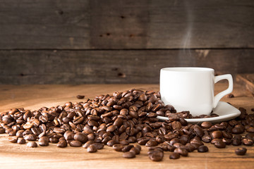 Cup of coffee with steam, roasted coffee beans