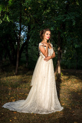 Beautiful bride in a wedding dress standing in the park, autumn time