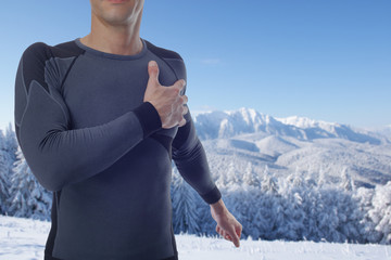 Fitness muscular man stretching after winter workout exercising in snowy mountain. Sport, recreation and healthy lifestyle concept