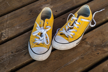 Cool teenager yellow sneakers on wooden background