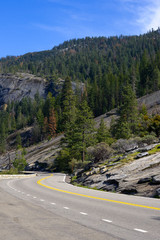 Curve road with rocks and mountain at the background.