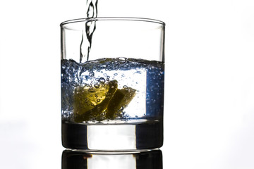 Slice yellow lemon in glass of water, motion action.