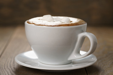 cup of cappuccino with marshmallow on wooden table, shallow focus